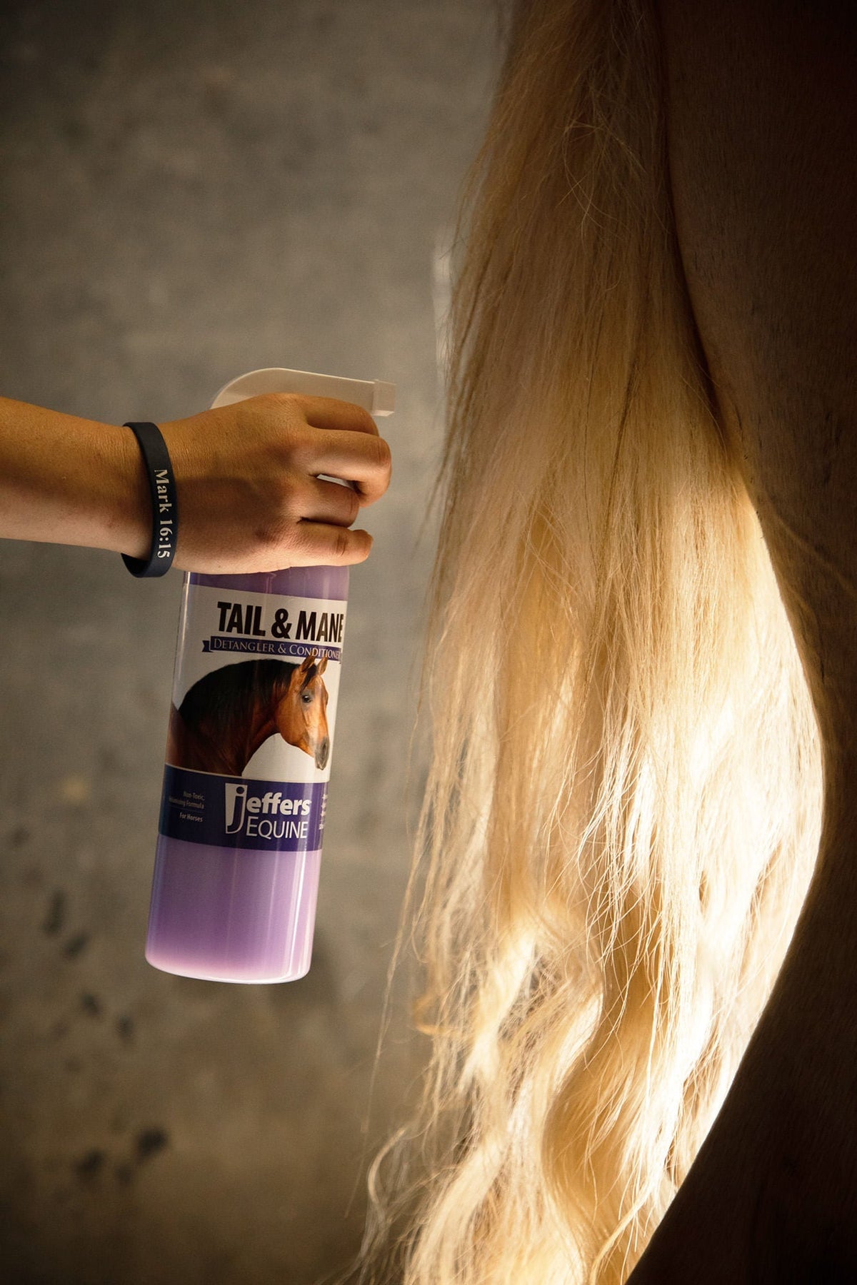 Horse tail and mane detangler spray bottle held beside a horse’s long mane