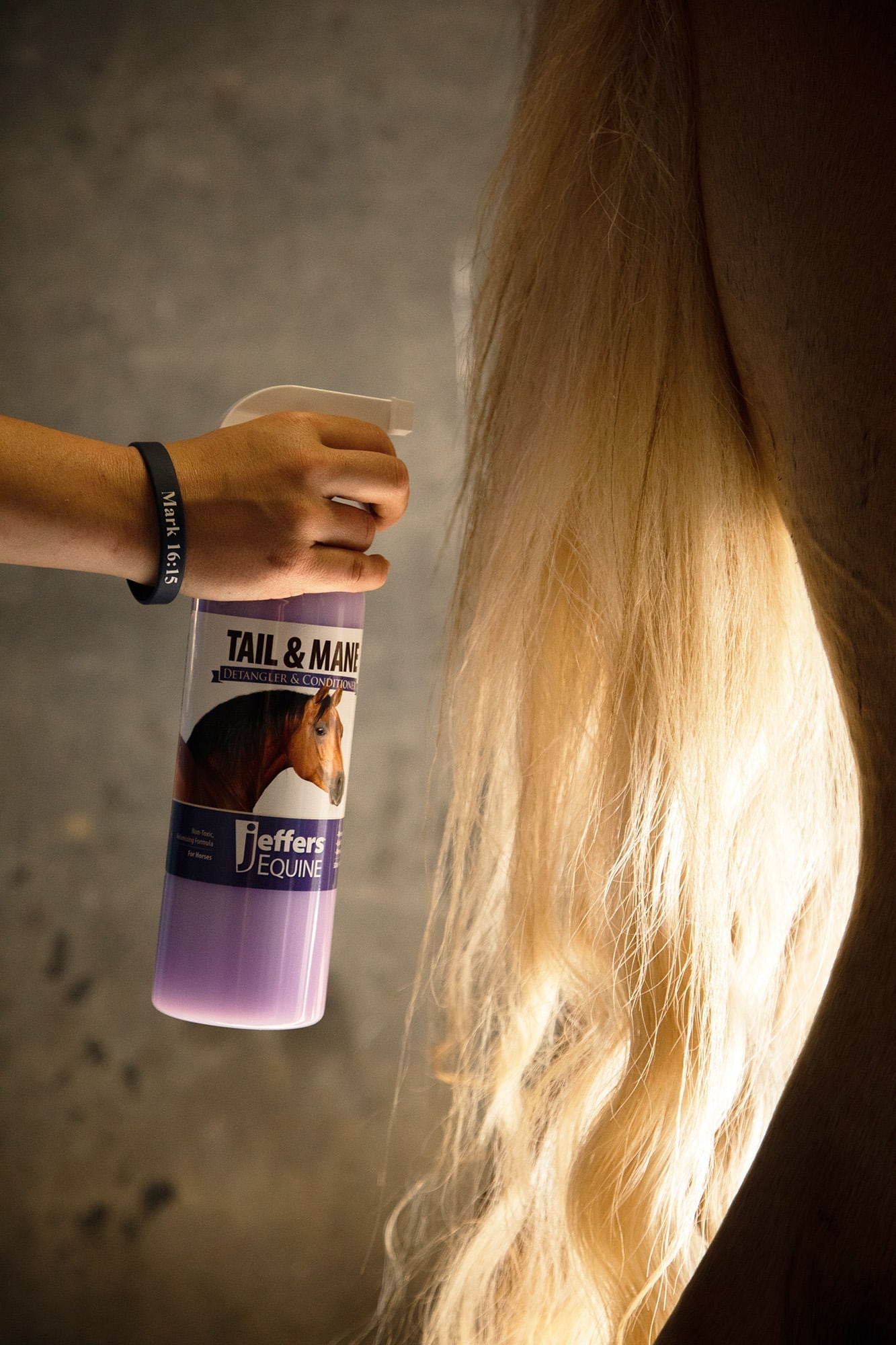 Horse tail and mane detangler spray bottle held beside a horse’s long mane
