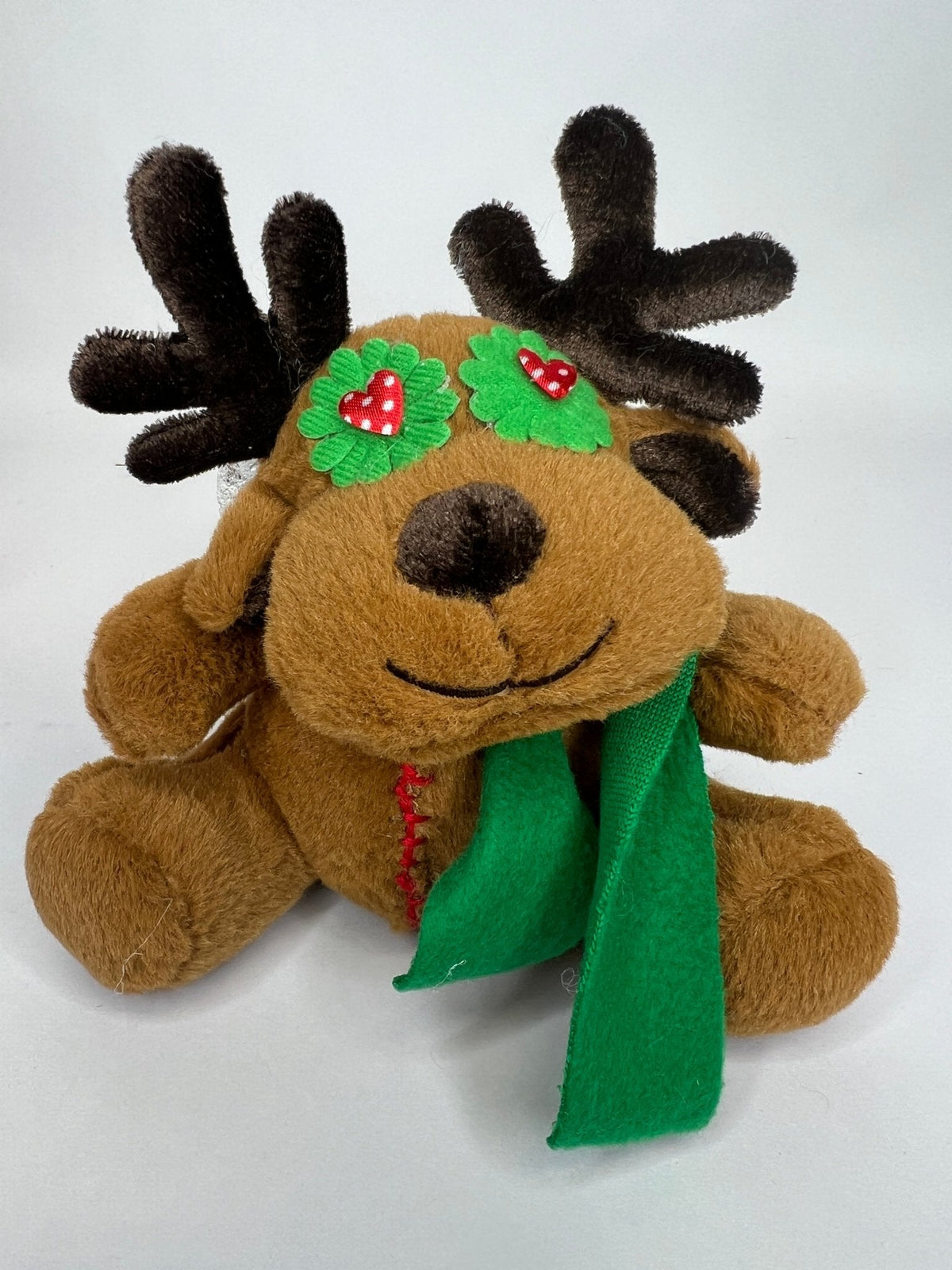 Brown reindeer plush with green scarf and festive holiday patches, soft stuffed toy