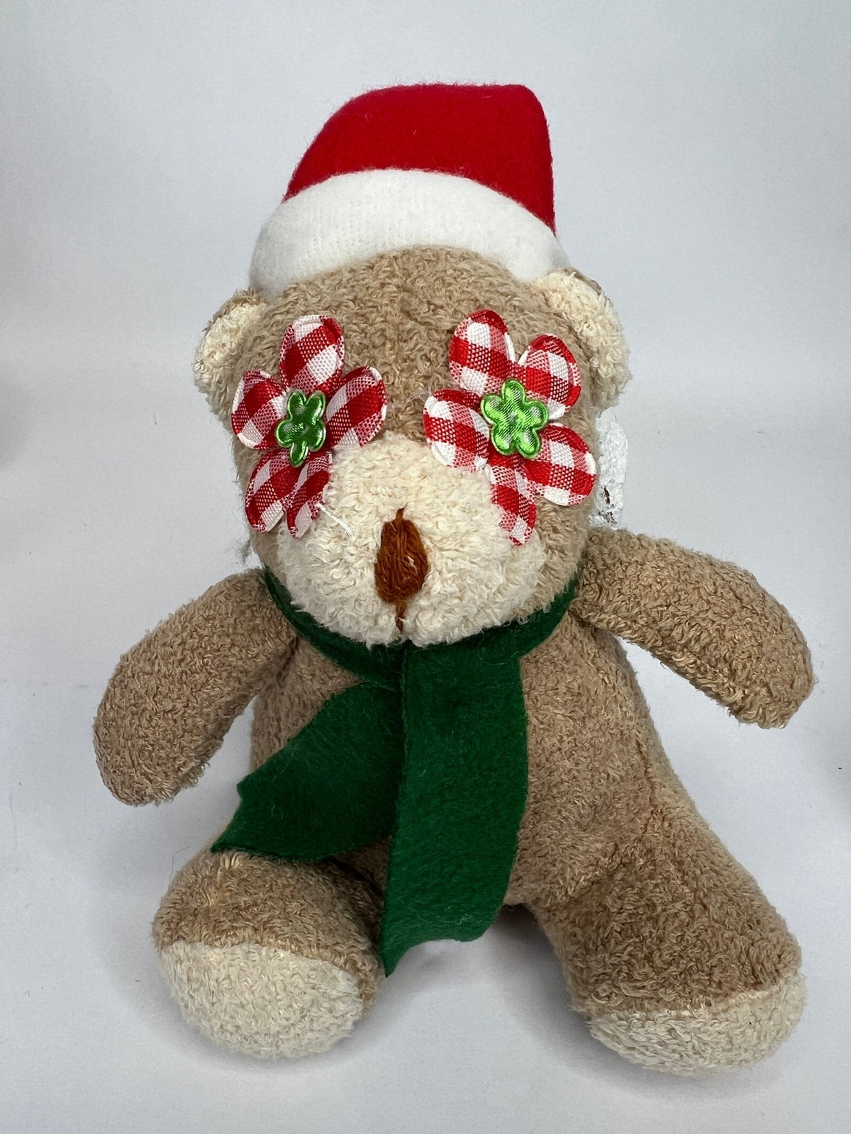 Tan teddy bear plush with red Santa hat, red-and-green plaid earmuffs, green scarf