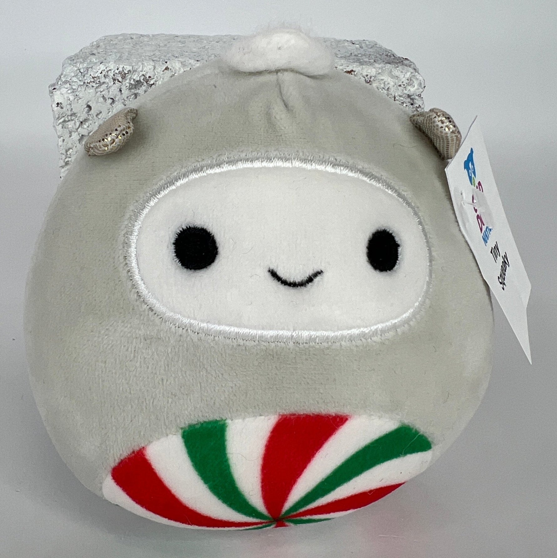 White peppermint holiday plush with metallic silver top and smiling face detail