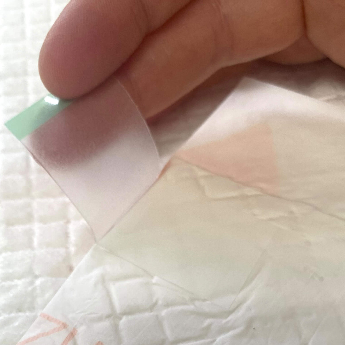 Folded training pad showing a green-and-white release tab, close-up detail