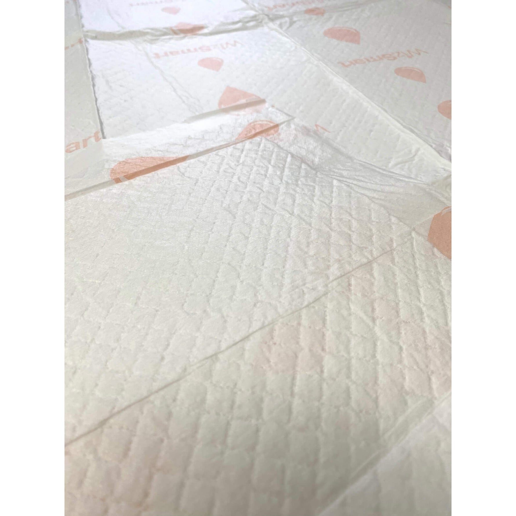 Off-white dog training pad surface with quilted texture and small pink heart markings